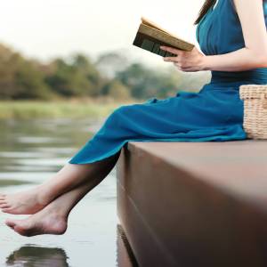 Woman reading while sitting on a dock