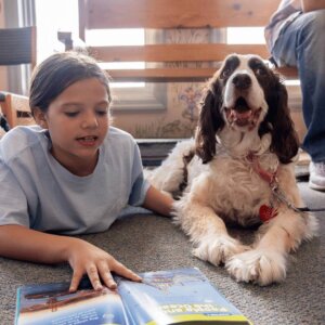 a child reading to a therapy dog