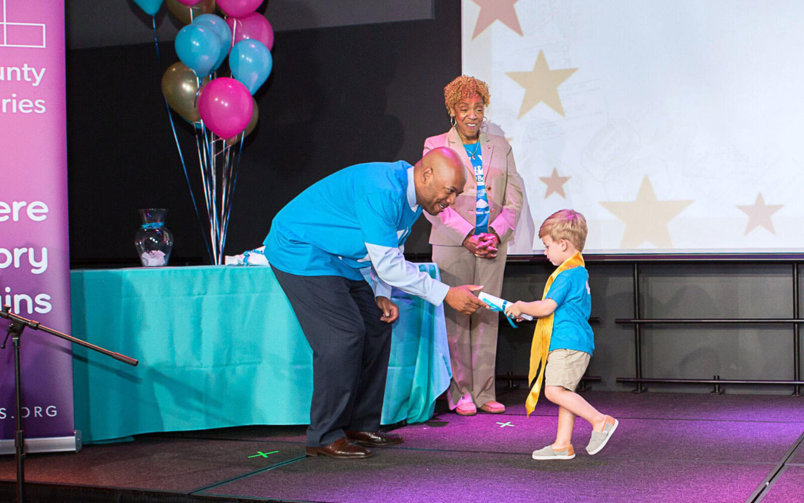 Robert Presenting Child Their 1000 Books Completion Certificate On Stage