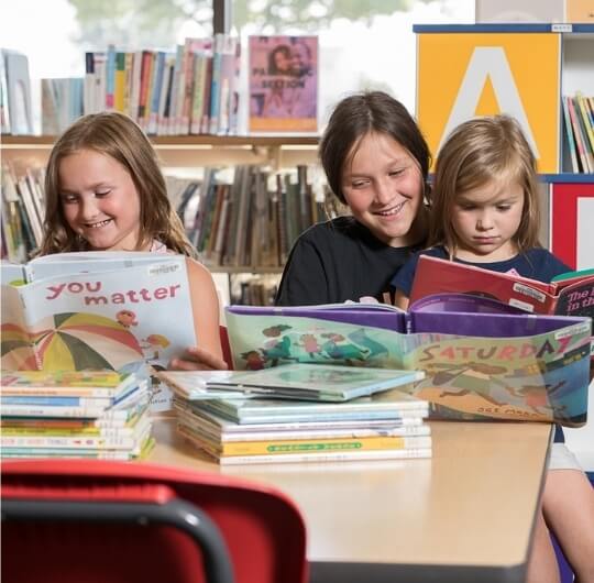 Three Girls Reading Children’s Books Inside Dover Library