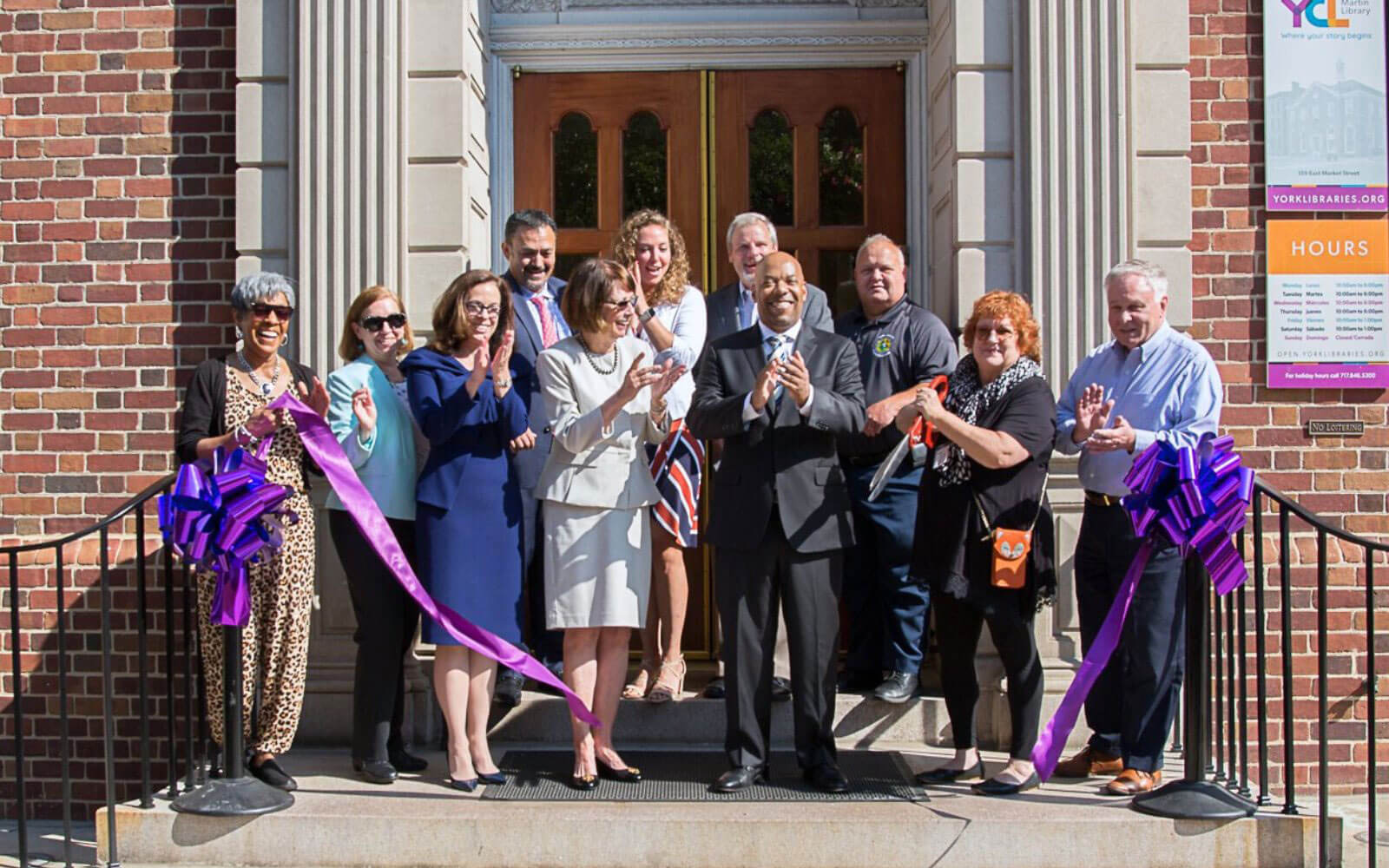 Group Of Community Leaders Cutting Ribbon Outside Martin Library Doors