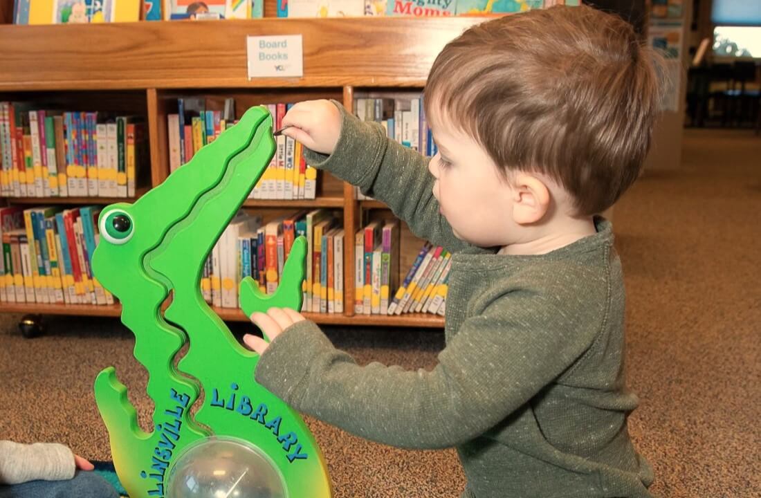 Little Boy Dropping Coin Into Dinosaur Piggy Bank