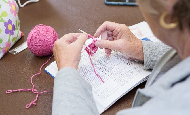 Close Up Of Hands Knitting Pink Yarn
