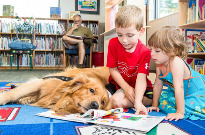 dog laying on floor while kids read aloud