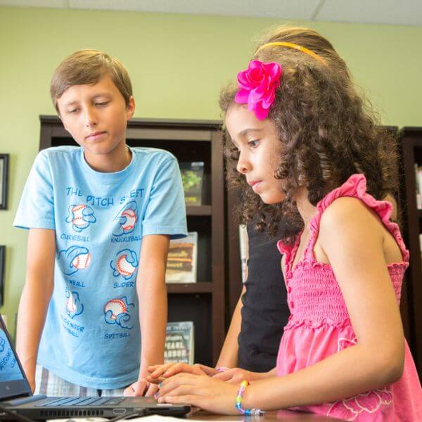 Three children using a laptop at Village Library