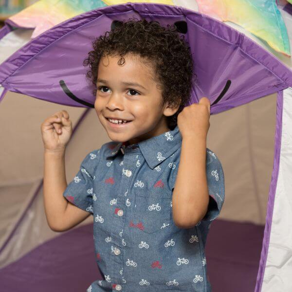 Smiling child playing in a tent