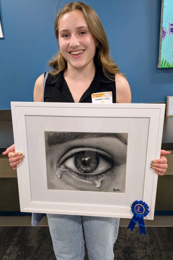 First Place Winner Jassalyn I. stands with her artwork and blue ribbon during the Do My Feelings Matter? Teen Art Show Opening