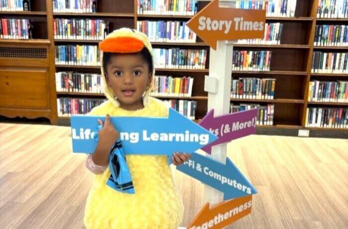 child-wearing-duck-costume-holding-literacy-for-change-sign