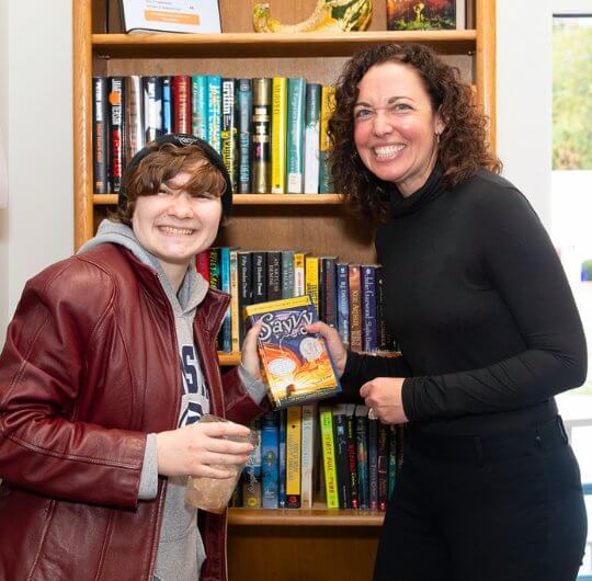 teen and adult holding a book together